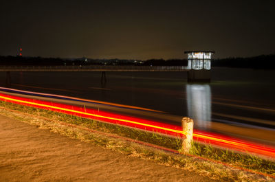 Light trails on road against sky at night