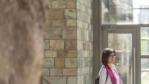 Young woman standing against wall