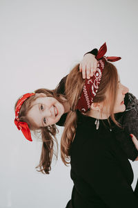 Happy woman carrying daughter against white background