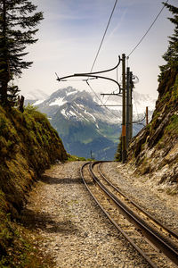 Railroad tracks by mountain against sky