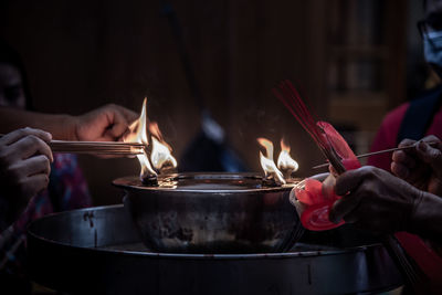 Midsection of person holding burning candles in temple