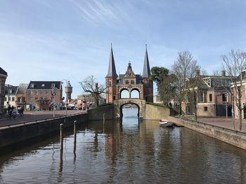 Bridge over river by buildings against sky in city