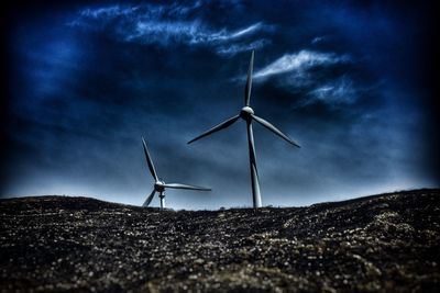 Low angle view of windmills against sky