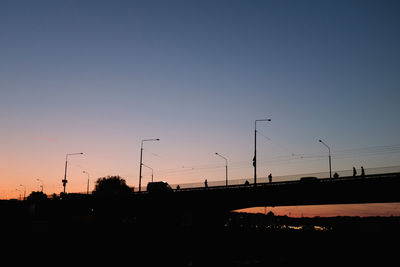 Silhouette street against clear sky at sunset