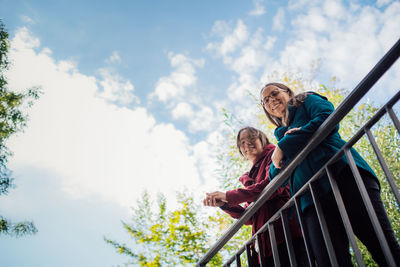 Low angle view of woman with arms raised against sky