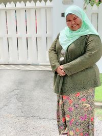 Portrait of a smiling young woman standing against wall