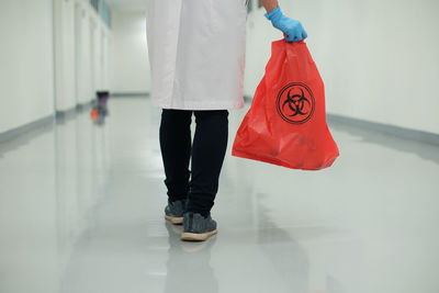 Low section of man with umbrella walking in corridor