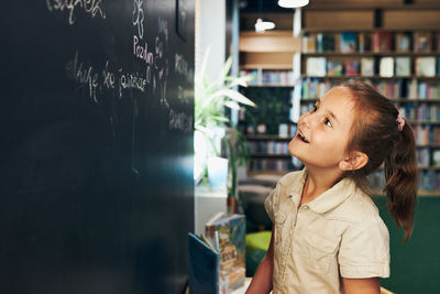 Little girl writing on blackboard. smart student put solve on chalkboard. back to school