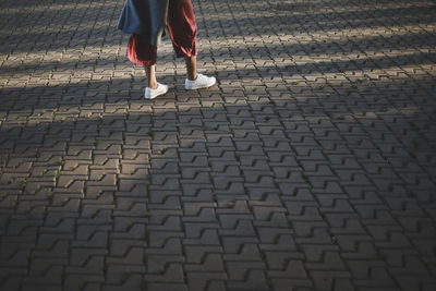 Low section of woman standing on cobblestone 