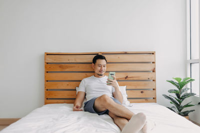 Man using phone while sitting on bed at home