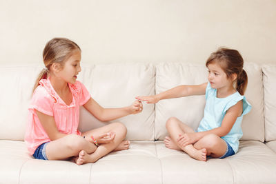 Sisters playing while sitting on sofa at home