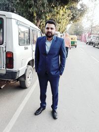 Portrait of young man standing on road in city