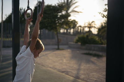 Boy hanging on gymnastic rings on playground at park
