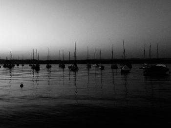Sailboats moored in sea against clear sky