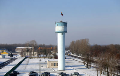 Lighthouse on snow covered landscape against sky