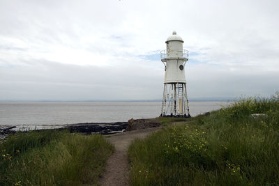 Lighthouse by sea against sky