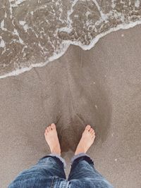 Low section of man standing on beach
