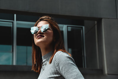 Young woman wearing sunglasses against building