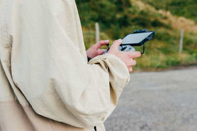 Midsection of woman holding umbrella on road