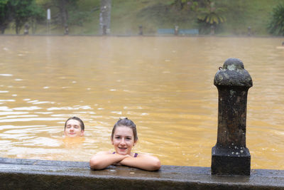 Teen girl and young man swimming in a mineral thermal pool in terra nostra park at furnas, azores