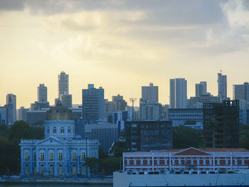 Buildings in city against cloudy sky