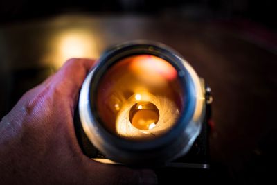 Cropped hand of person holding illuminated lens