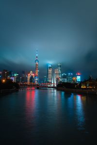 Illuminated city by river at night