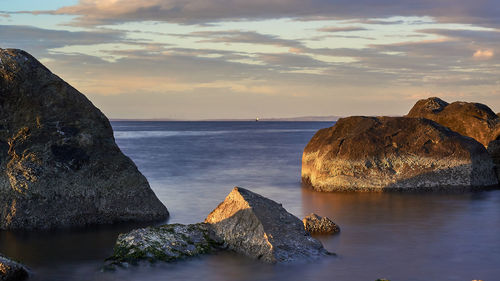 Rocks on beach against sky during sunset