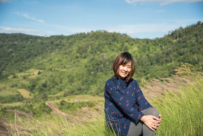 Woman smiling on field against sky