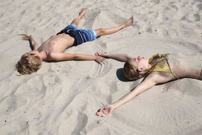 Boy and girl lying on sandy beach