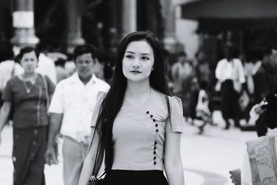 Young woman looking away while standing in city