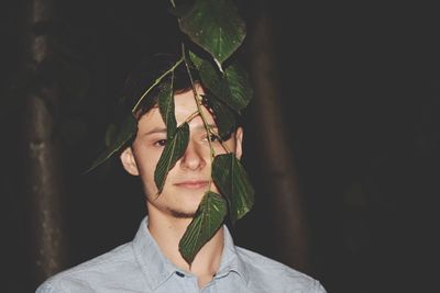 Young man by twig of plant at night