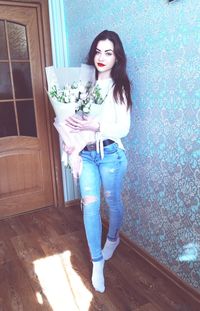 Portrait of smiling young woman standing against wall