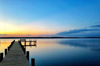 Pier over lake against sky during sunset