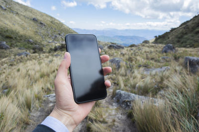Midsection of person using mobile phone in mountains