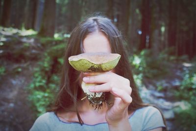 Woman hiding face behind mushroom