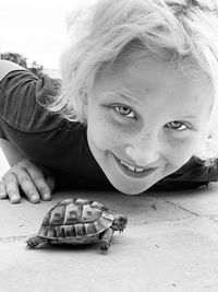 Portrait of smiling girl lying by tortoise on floor