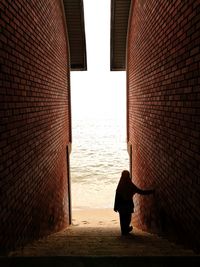 Rear view of woman standing by sea against sky