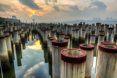 Rusty columns in lake against sky during sunset