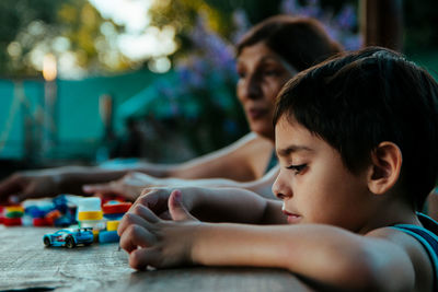 Close-up of boy playing with toys by grandmother on table