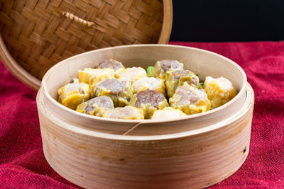 Close-up of dim sums in bamboo container on napkin