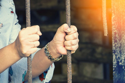 Midsection of woman holding rusty railing