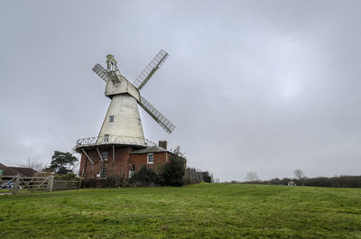 A white smock mill built in 1869 onto a two storey red brick base with attached millers cottage,