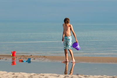 Rear view of shirtless boy on beach