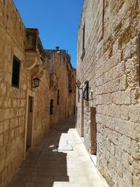 Footpath amidst buildings against sky