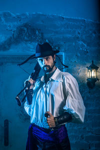 Portrait of man in costume standing against door of abandoned building at night