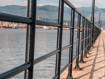 Railing by sea against mountain