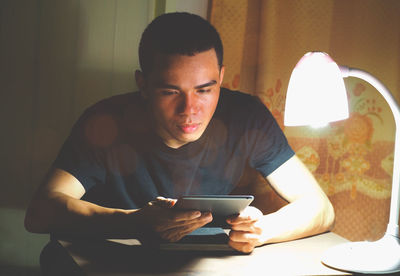 Young man using mobile phone while sitting on table