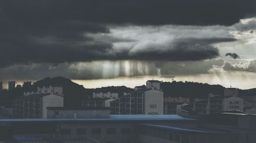 Buildings in city against dramatic sky