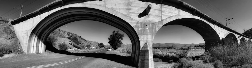 Arch bridge by road against sky